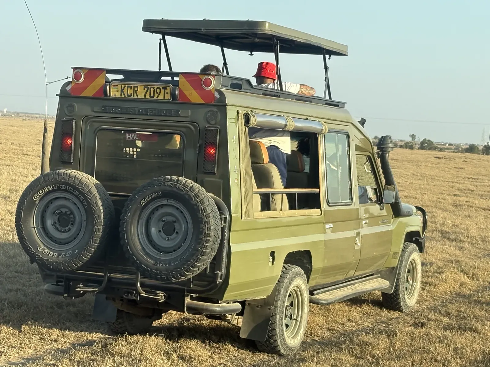 A safari vehicle on open grassland during the team's game drive