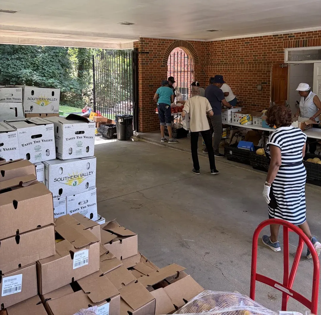 Volunteers loading and handing out boxes of fresh produce under the church portico
